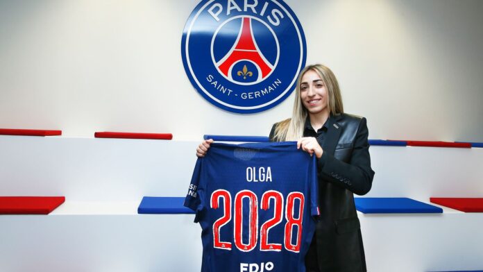 Olga Carmona a signé au PSG jusqu'en 2028. On la voit souriante tenir son nouveau maillot avec l'inscription 2028 dessus.