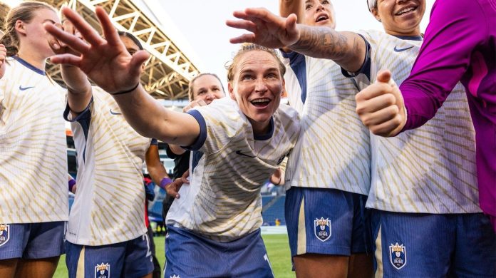 La joueuse et capitaine Jess Fishlock entouré en cercle de son équipe et staff du Seattle Reign